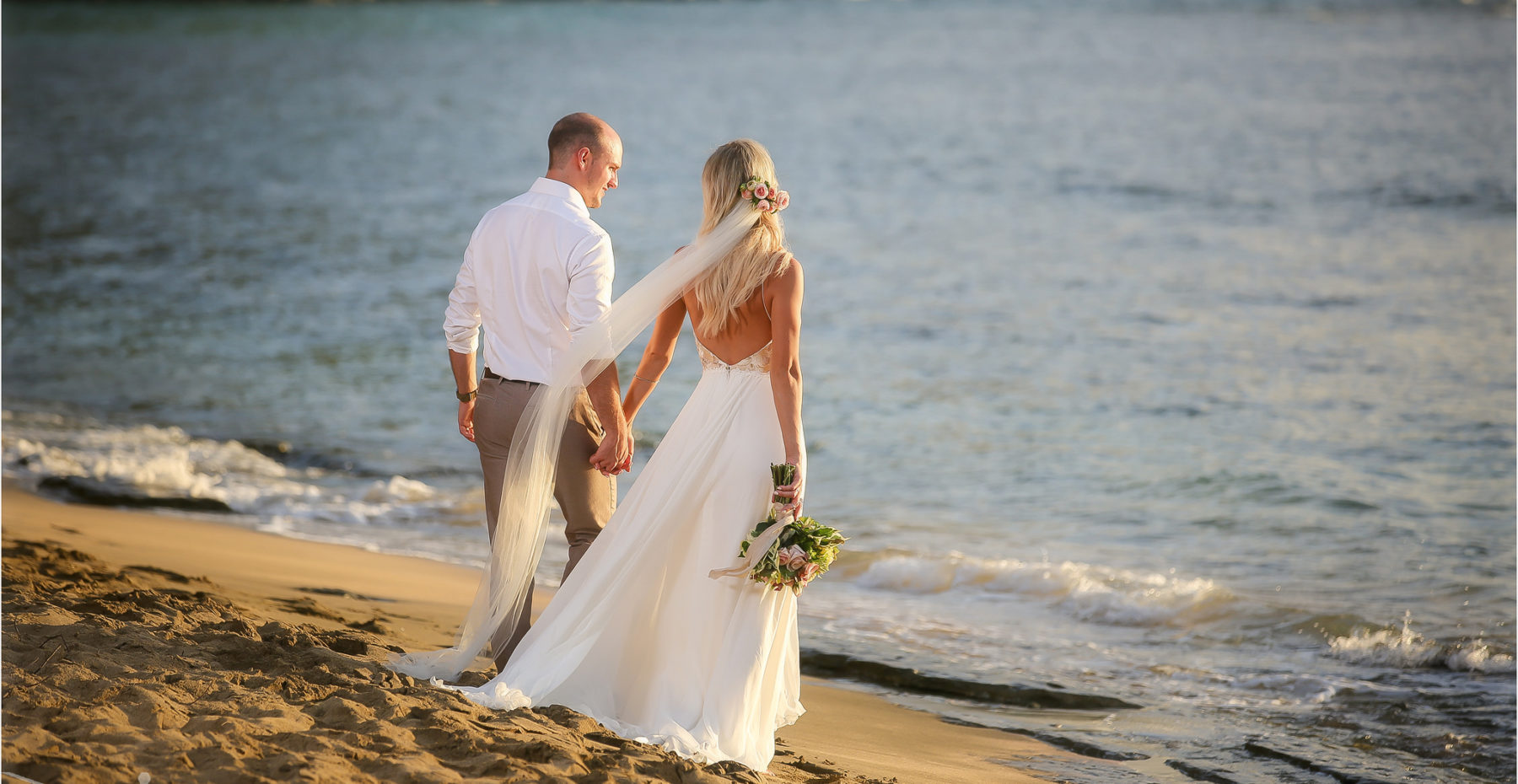 Newlywed couple hand in hand enjoying the ocean after their romantic beach elopement