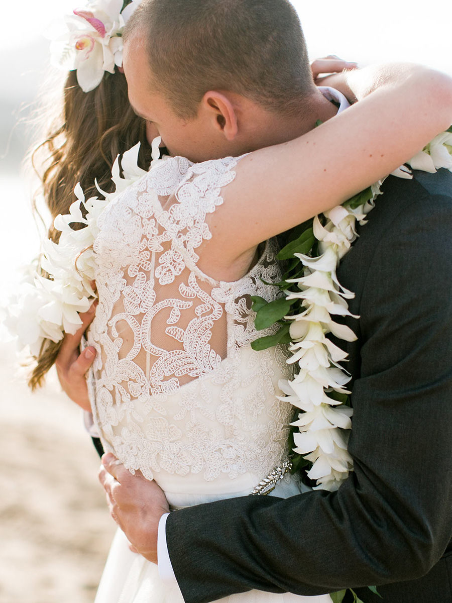 Couples embrace at their beach wedding on Kauai.