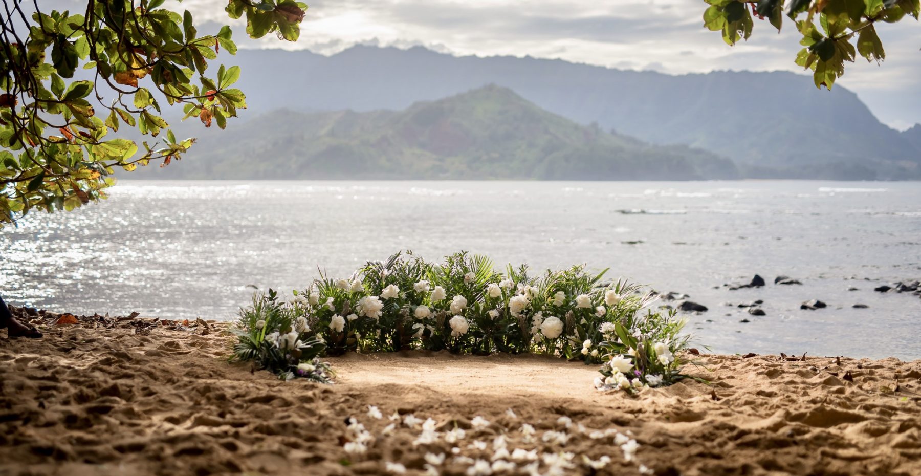 Lush green and white semi-circle of flowers for a beach elopement on Kauai