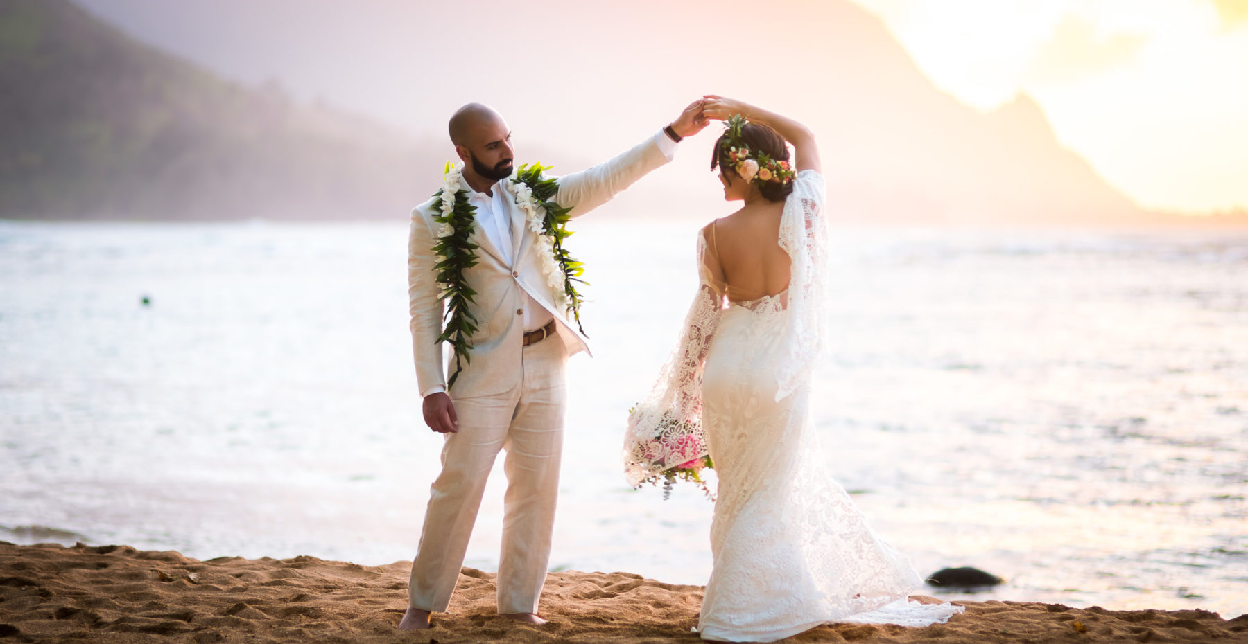 Groom holding bride in the ocean at sunset