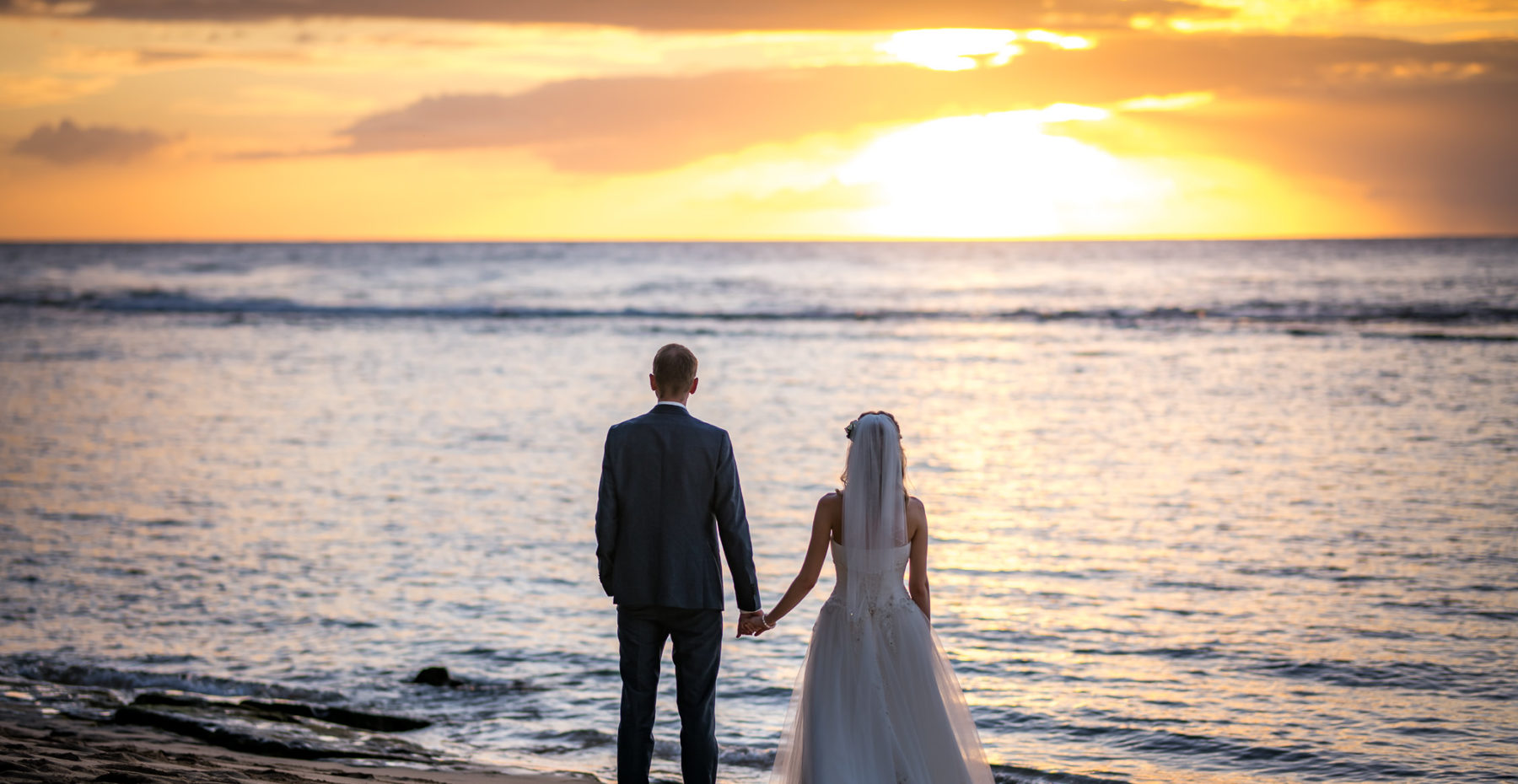 Romantic elopement with the groom awaiting his bride in a flower circle on a beautiful Kauai beach at sunset